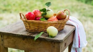 Jabłka w koszyczku na stole na łonie natury